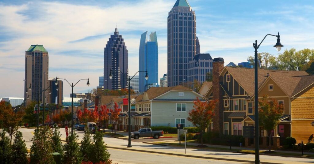 Two-story suburban homes line a residential street in Midtown Atlanta with multiple skyscrapers in the background.