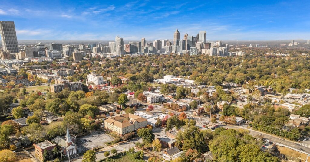 An aerial view of a neighborhood outside of Atlanta in early fall. The Atlanta skyline is in the distance under a blue sky.
