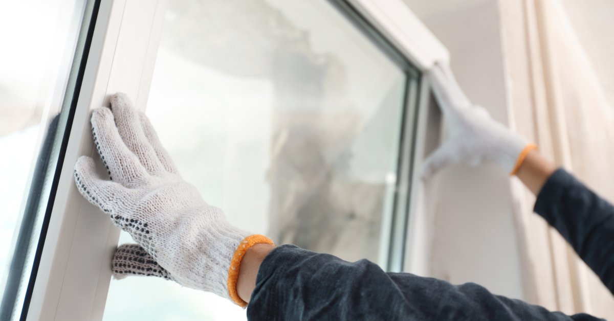 A close-up of a person wearing white gloves. They're pushing a window panel into place inside a home.
