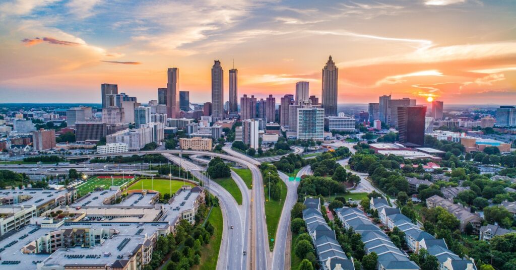 The skyline of Atlanta, Georgia. Houses and the interstate are in the foreground, and tall buildings are in the distance.